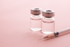 Syringe and vial of compounded semaglutide on pink background