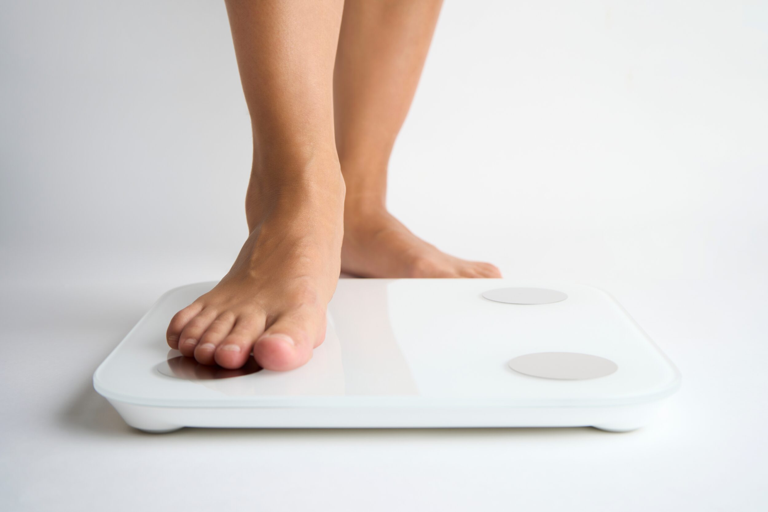 Close up of someone stepping on a scale after using semaglutide for weight loss