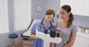 Practitioner weighing patient using GLP-1 for weight loss monitoring