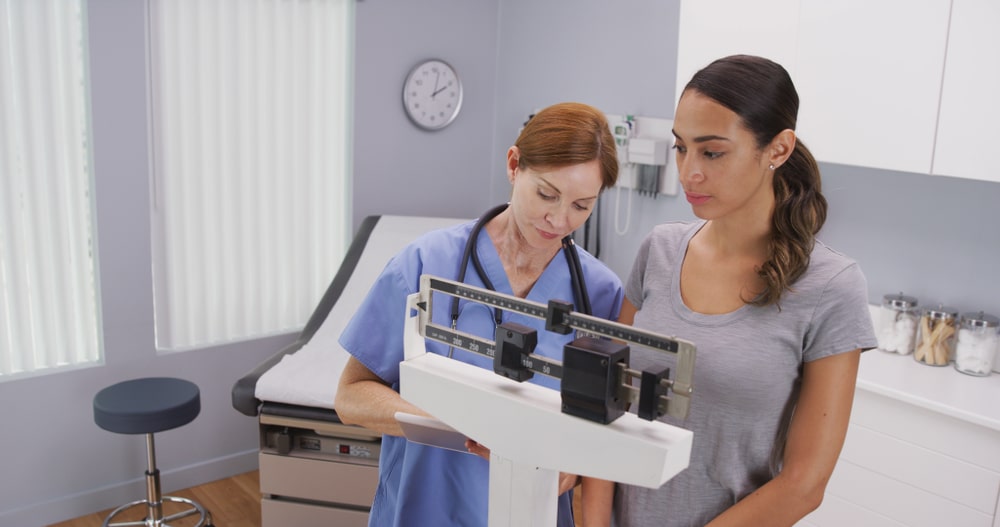 Practitioner weighing patient using GLP-1 for weight loss monitoring