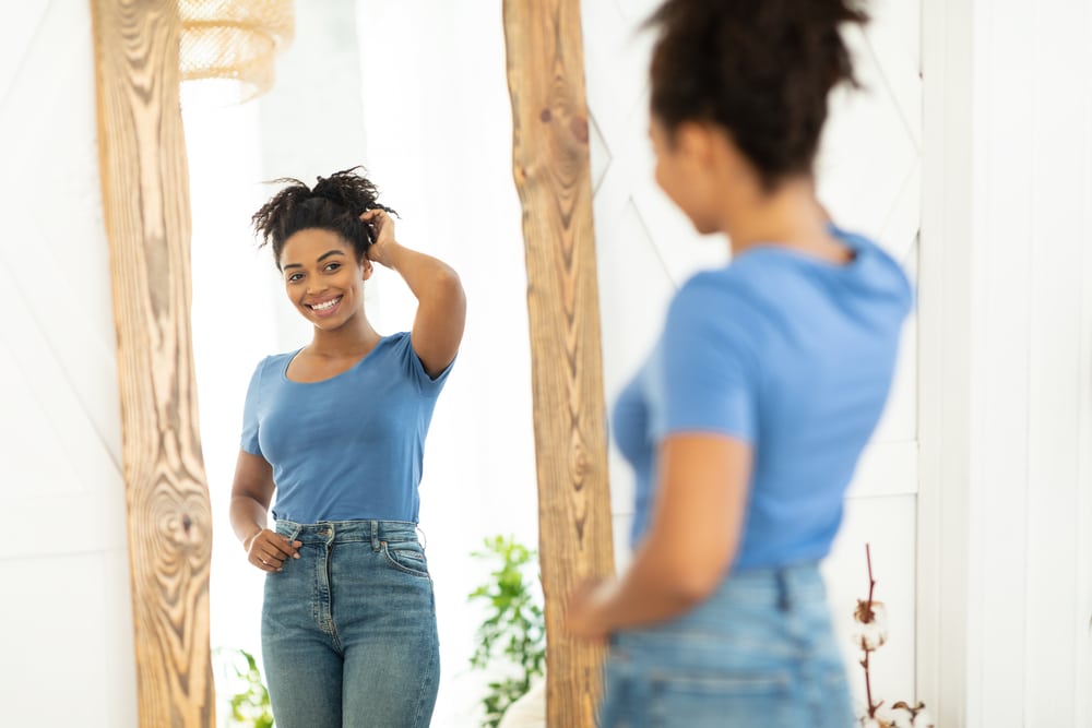 Woman smiling at her reflection during GLP-1 weight loss treatment