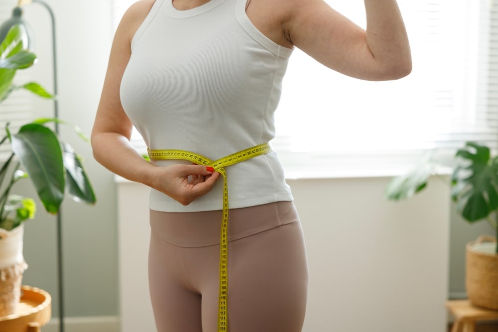 Woman measuring waistline during GLP-1 weight loss treatment