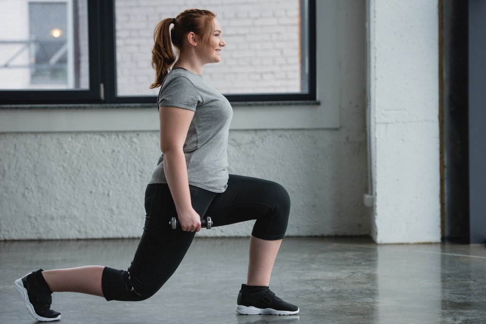 Woman doing lunges with dumbbells to support muscle mass during GLP-1 weight loss.