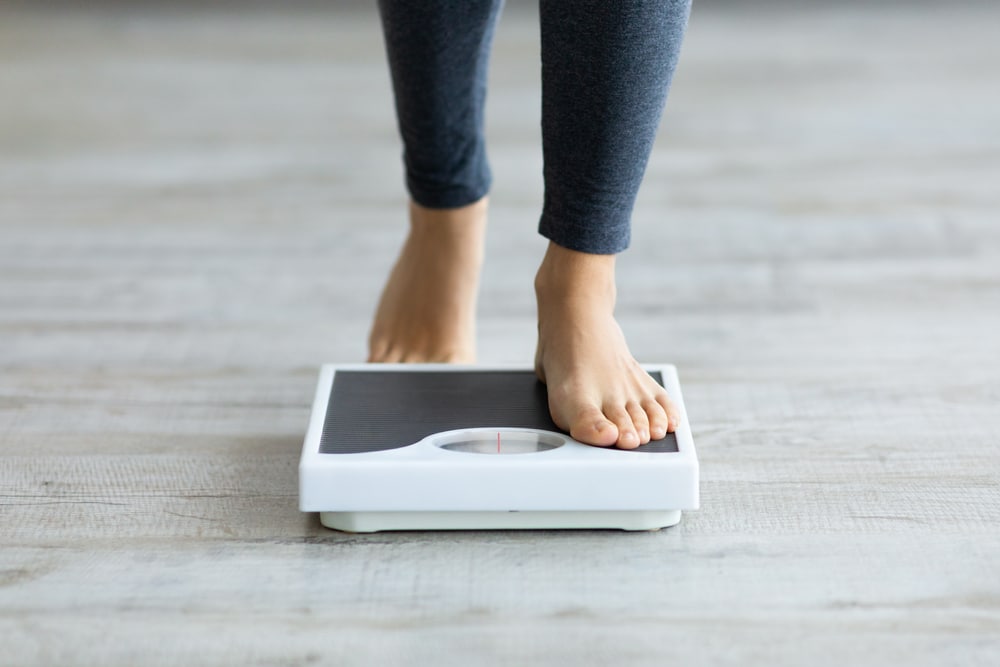 Feet stepping onto a scale during GLP-1 weight loss progress.