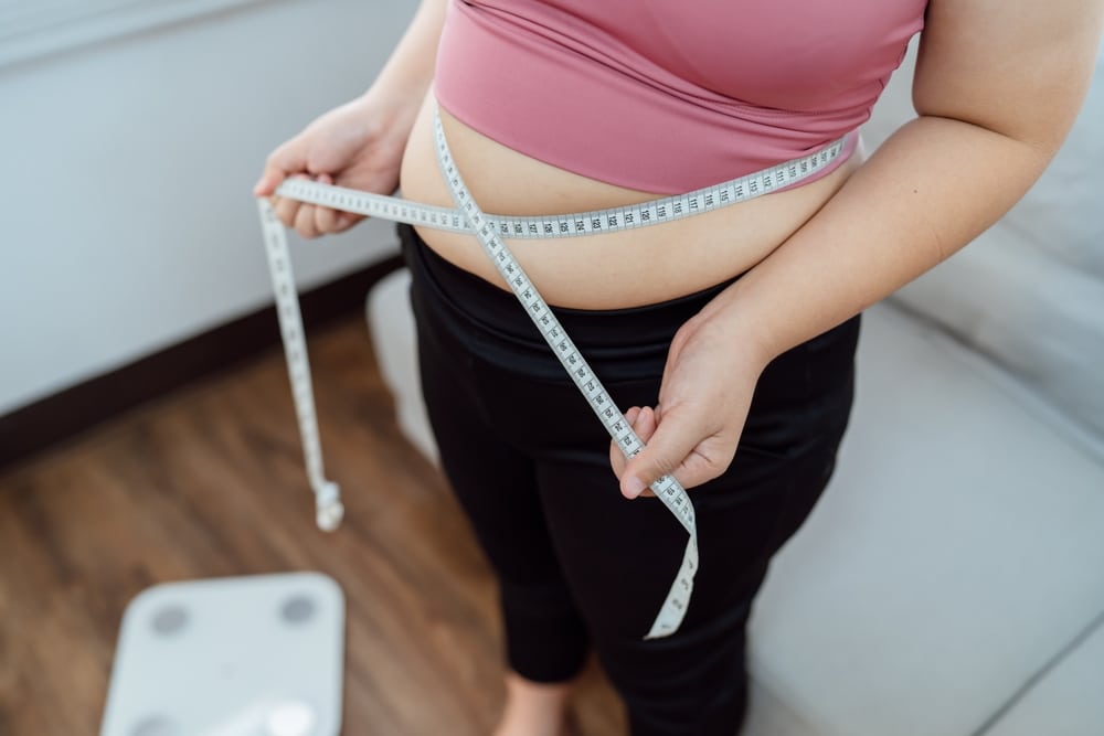 Person measuring their waist while tracking GLP-1 dose progress.